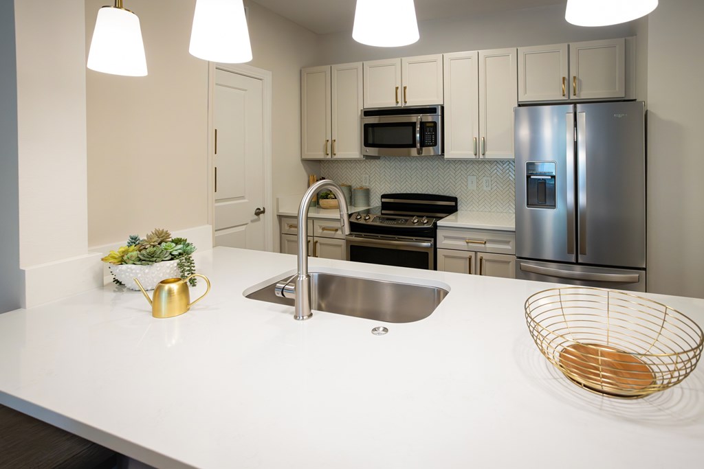 A modern kitchen with a white countertop and stainless steel appliances.