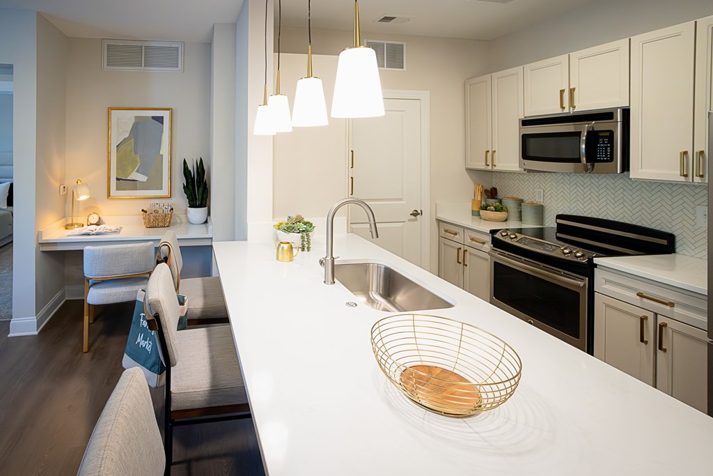 A modern kitchen with a white countertop and stainless steel appliances.