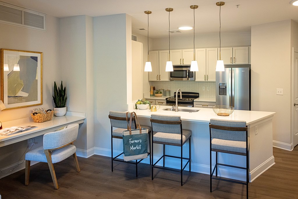 A kitchen with a white counter top and bar stools.