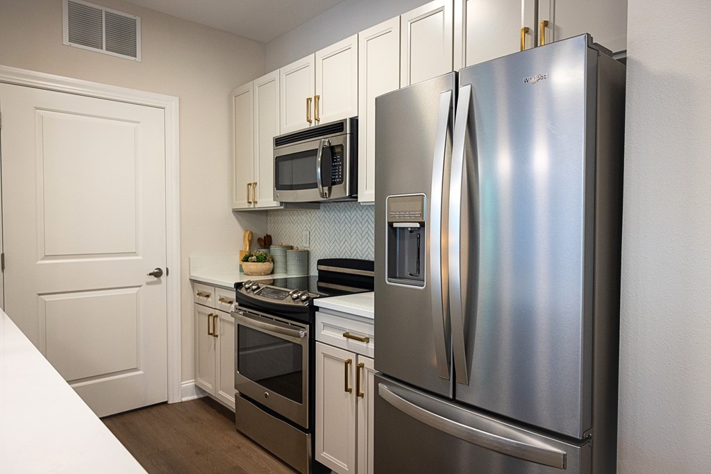 A kitchen with a stainless steel refrigerator, microwave, and oven.