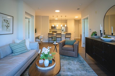 A living room with a grey couch and a coffee table with a vase of flowers on it.