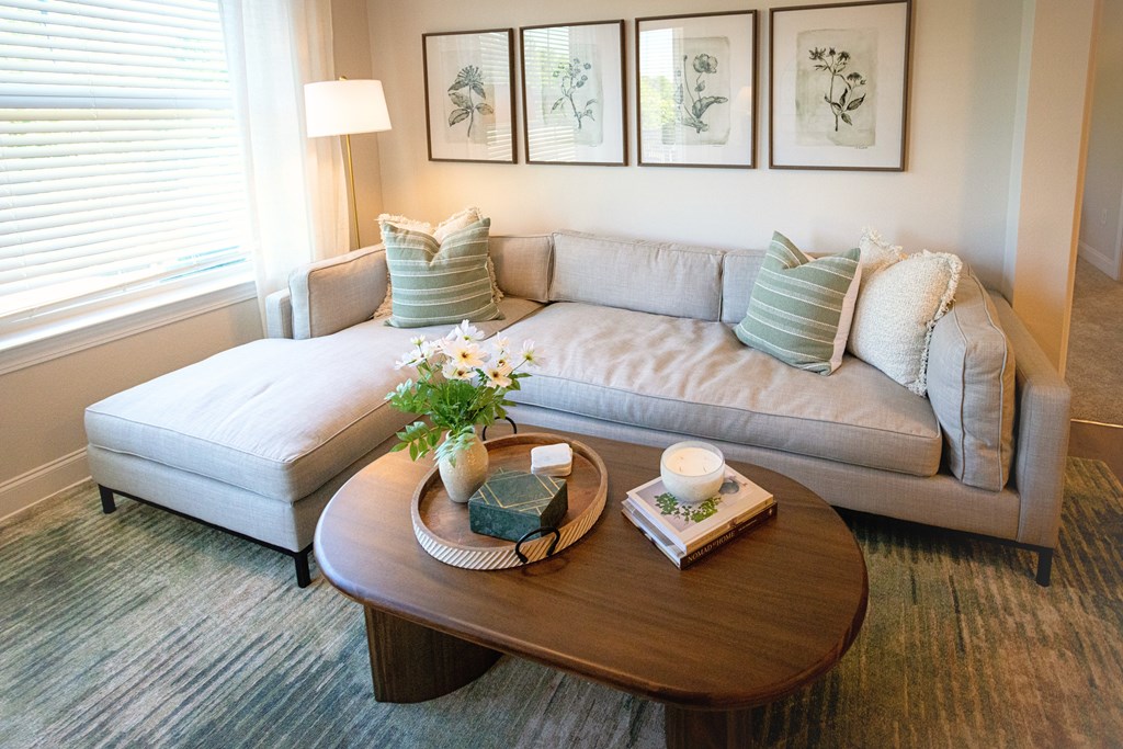 A living room with a grey couch, a coffee table, and three framed pictures on the wall.