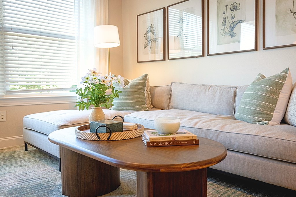 A living room with a couch, a coffee table, and a window with blinds.