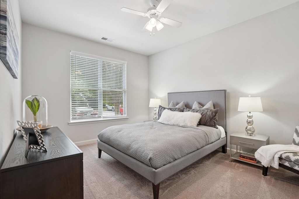 A bedroom with a bed, nightstand, and a ceiling fan.
