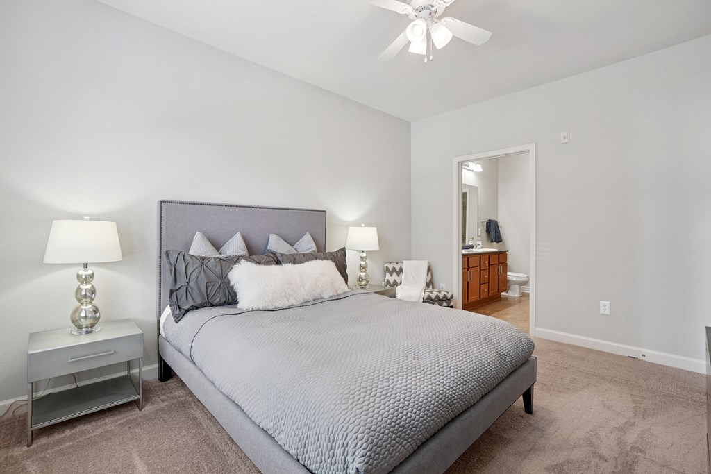 A bedroom with a large bed and a ceiling fan.