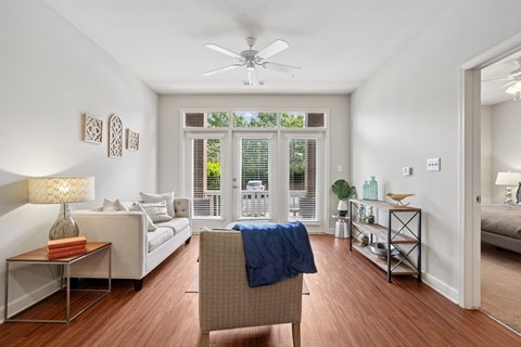 A living room with a sofa, a chair, and a table with a lamp on it.