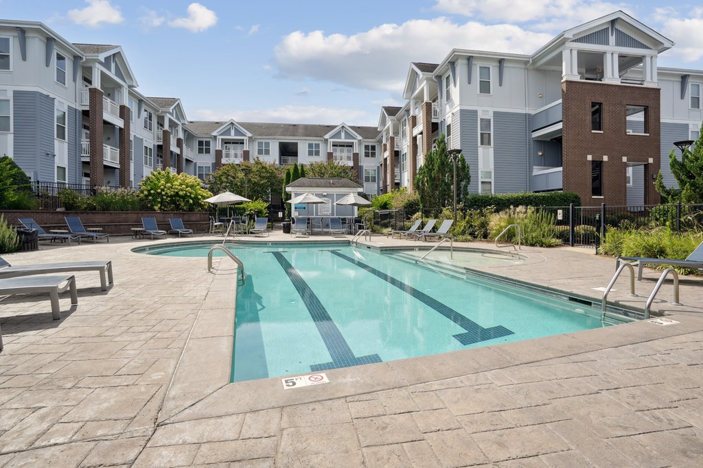 A swimming pool in a residential area with apartment buildings in the background.