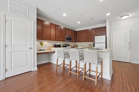 A kitchen with white cabinets and a white island with four chairs.
