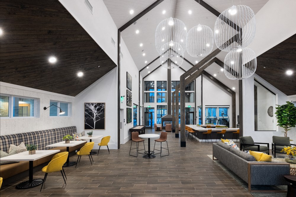A modern dining area with wooden floors and a mix of yellow and black chairs.