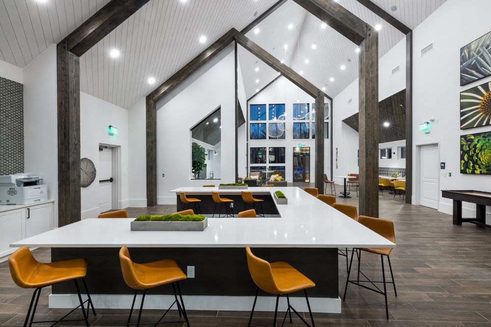 A white table with orange chairs is in the foreground of a modern room.
