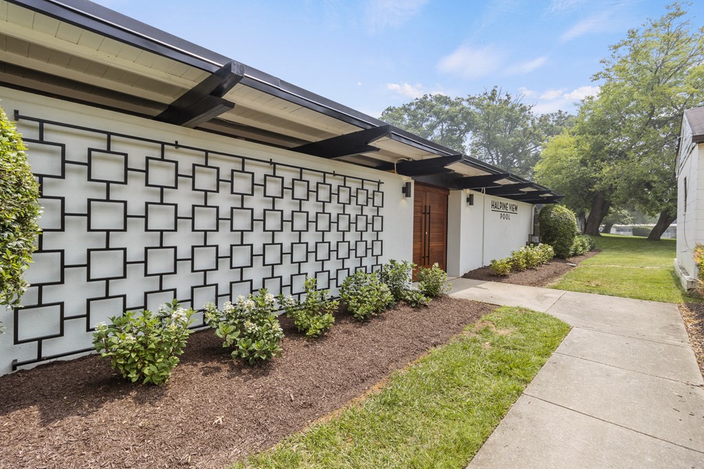 a white building with a white garage door and a white facade with a black roof and a