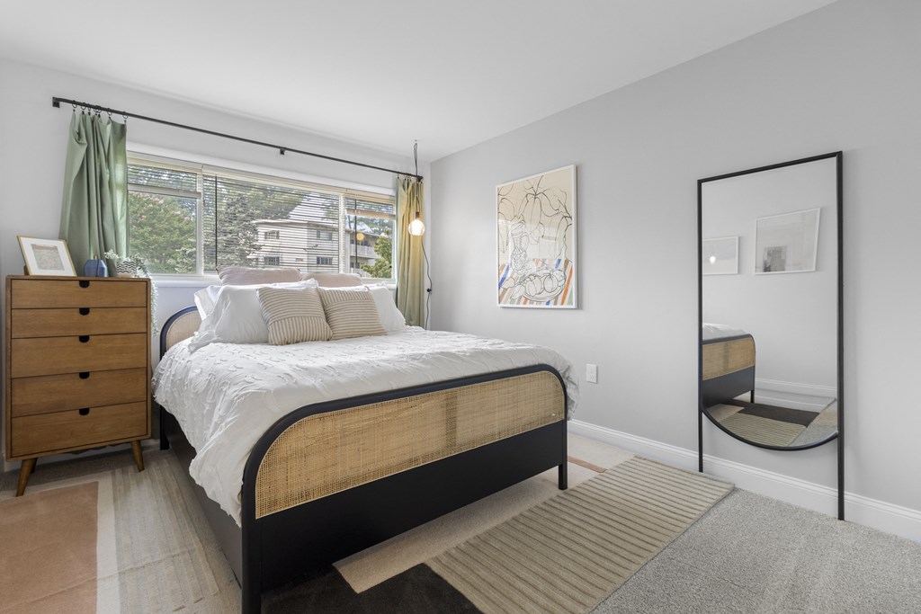 a bedroom with a large window and a large bed with a white comforter