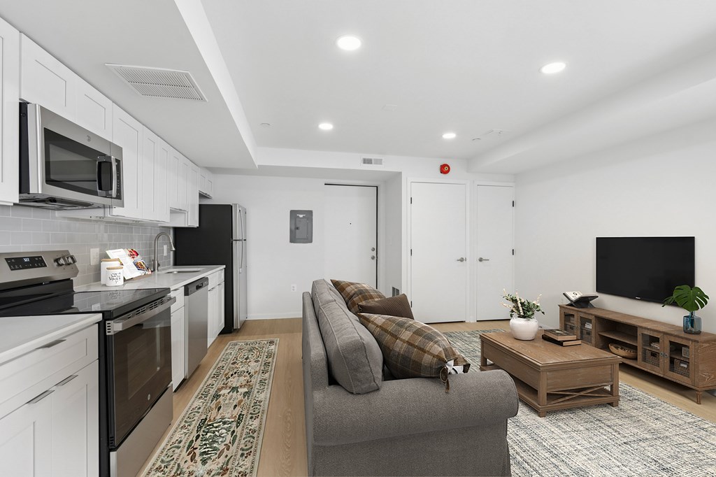 A modern kitchen with a grey couch and a wooden coffee table.