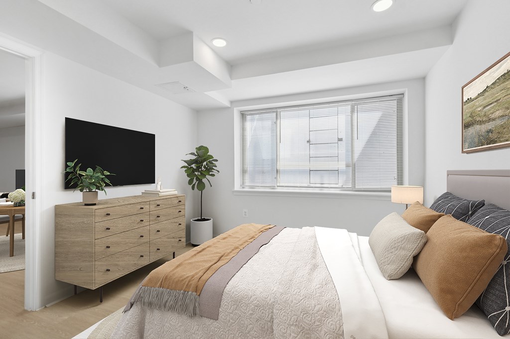 A bedroom with a large bed and a dresser with a plant on top.