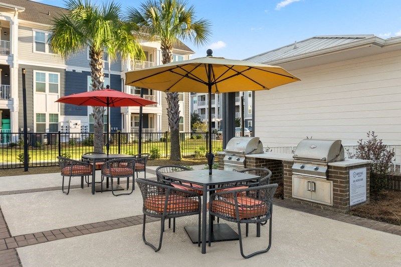 a patio with a grill and tables with umbrellas