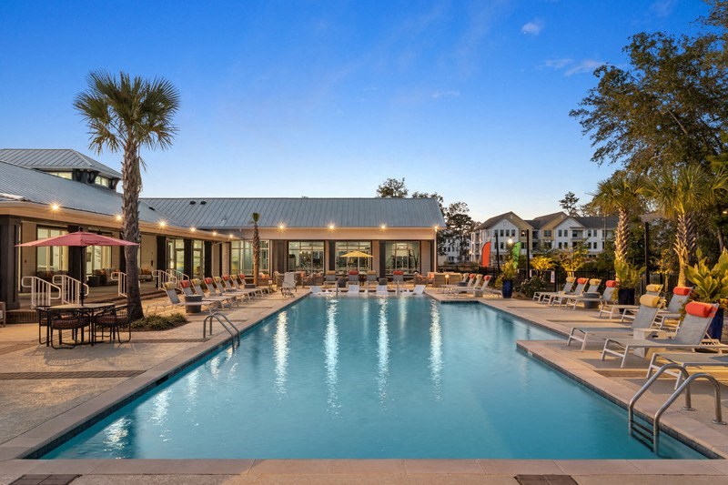 a swimming pool with chaise lounge chairs and a building in the background