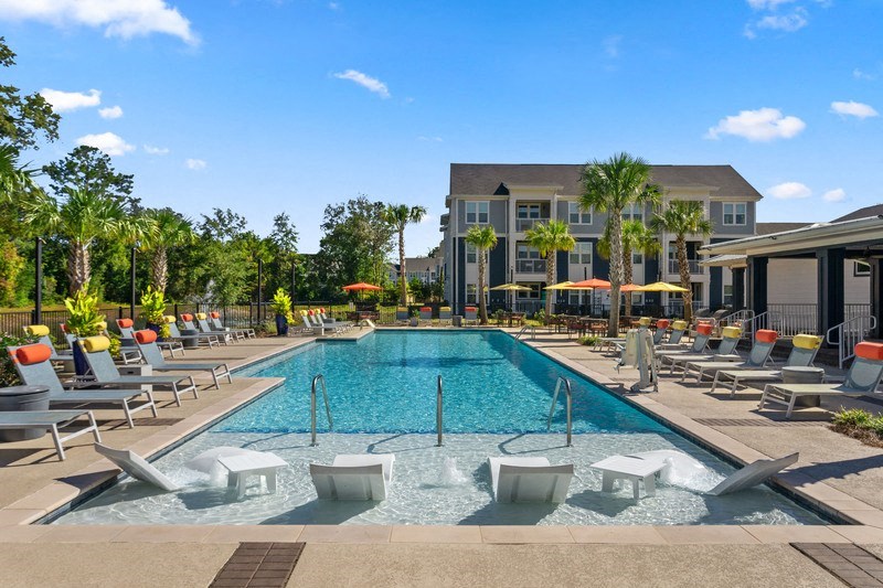 a swimming pool with lounge chairs and umbrellas in front of a building