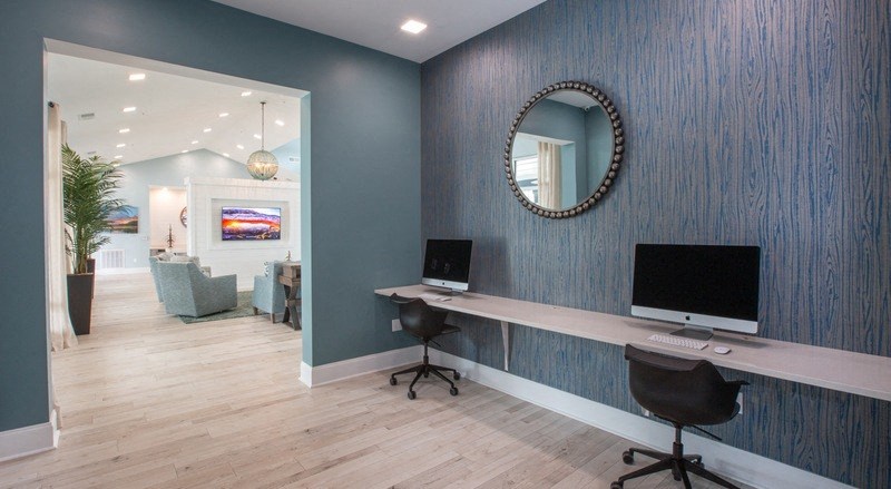 a room with a desk with a computer and a mirror