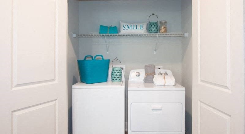 a small bathroom with a washer and dryer and a shelf above the sink