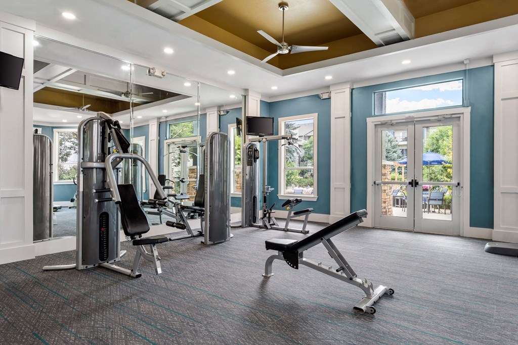 a gym with exercise equipment and windows in a building with blue walls
