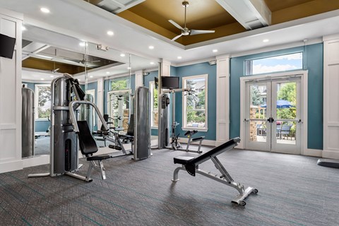 a gym with exercise equipment and windows in a building with blue walls