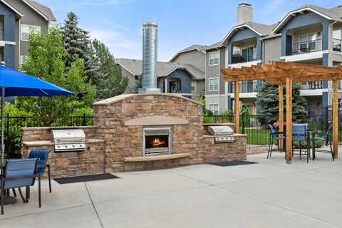 a backyard with a stone fireplace and a barbecue grill