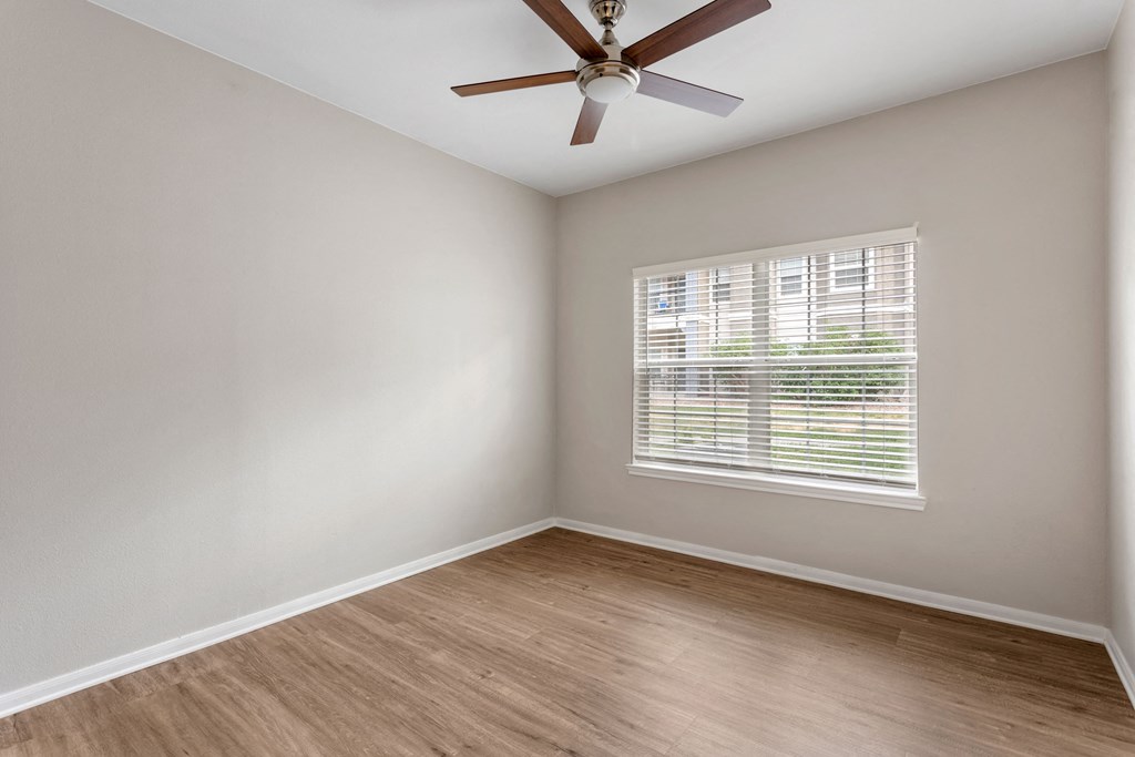 an empty room with a ceiling fan and a window