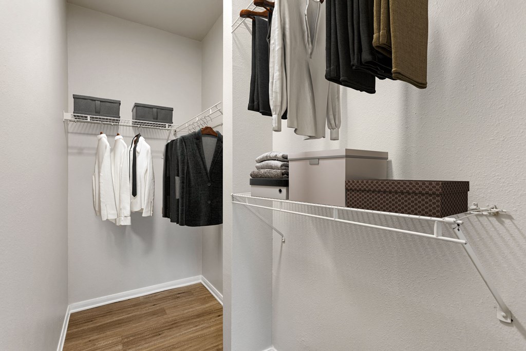 a walk in closet with a rack of clothes and a closet with rack of towels