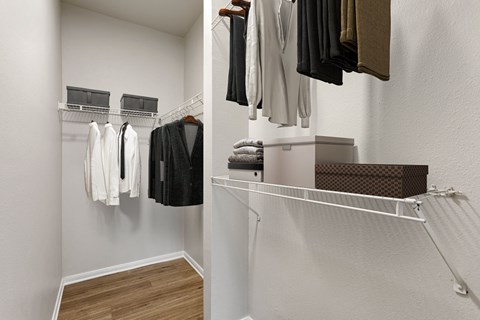 a walk in closet with a rack of clothes and a closet with rack of towels