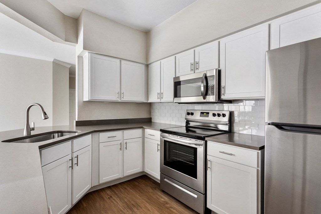 an empty kitchen with white cabinets and stainless steel appliances