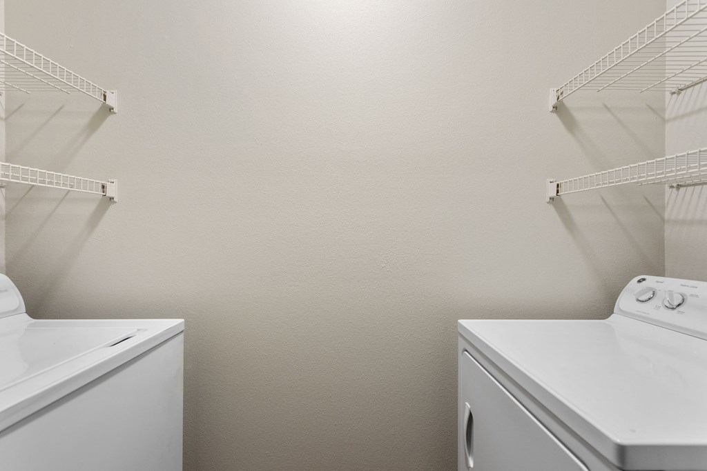 an empty laundry room with two washes and a dryer