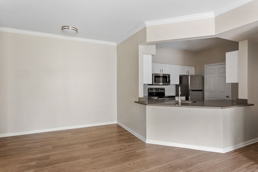 an empty apartment with a kitchen and a hard wood floor