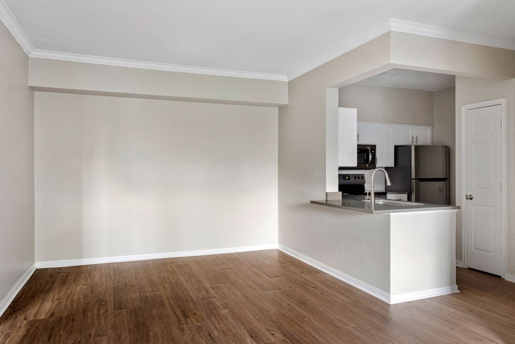 an empty apartment with a kitchen and a hard wood floor