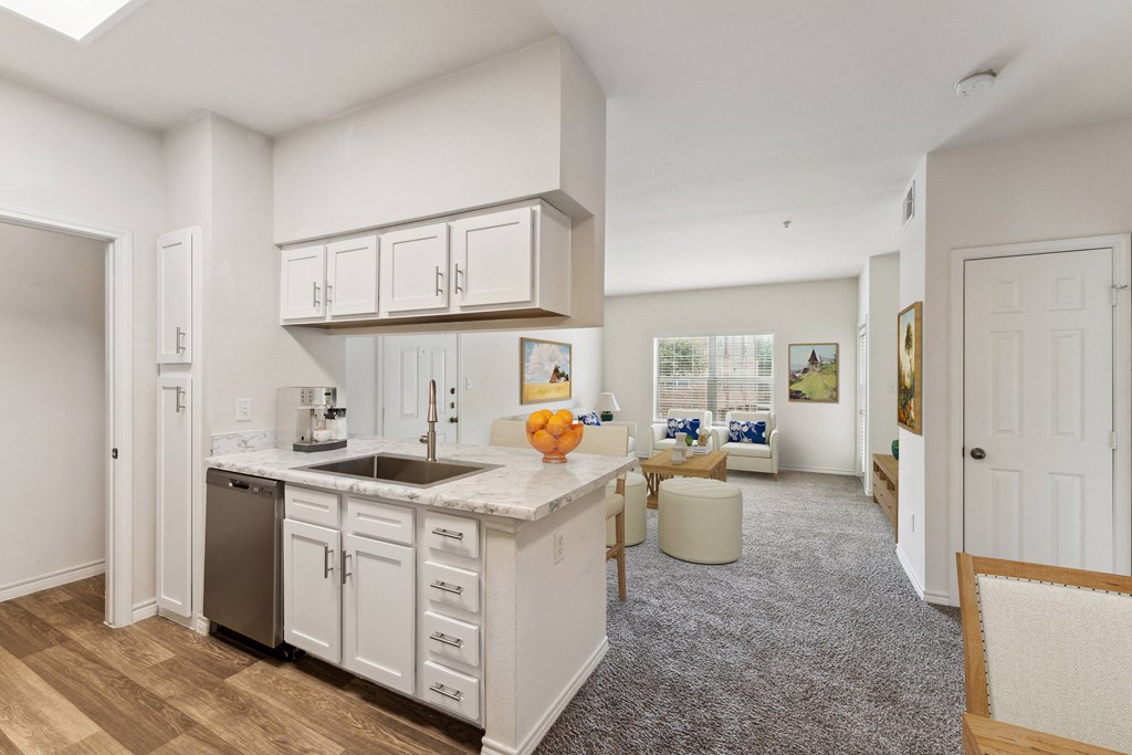 an open kitchen and living room with white cabinets and a sink
