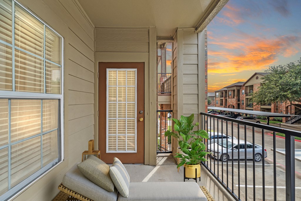 a front porch with a couch and a door and a sunset