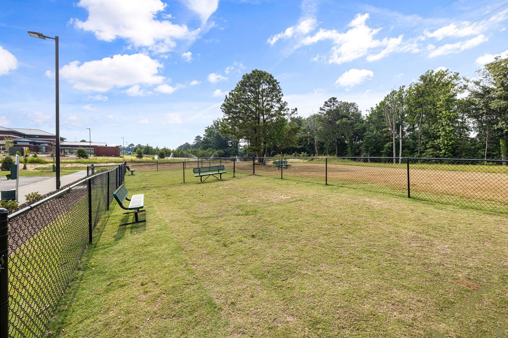 a dog park with a fenced in area and trees in the background