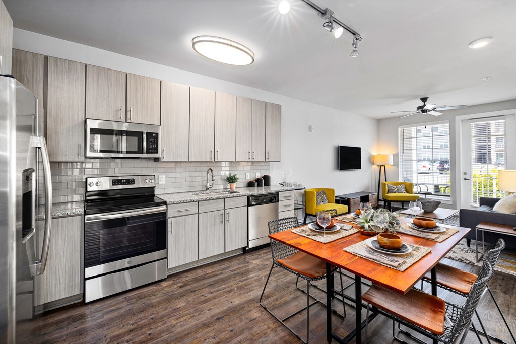 a kitchen with white cabinets and stainless steel appliances and a wooden dining table with yellow chairs