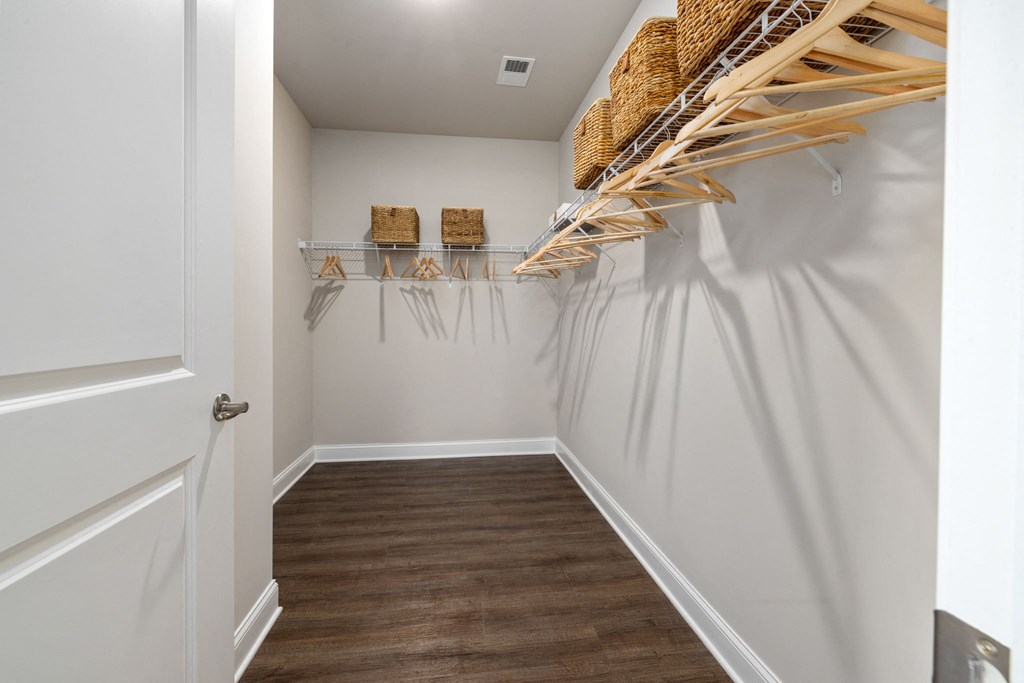a walk in closet with a white door and a wooden floor
