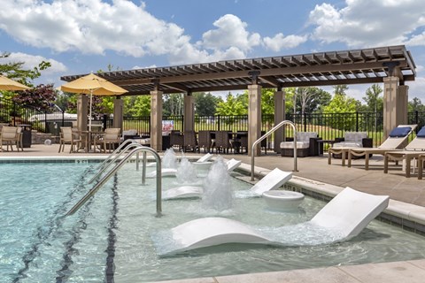 A pool with a waterfall and a pergola.