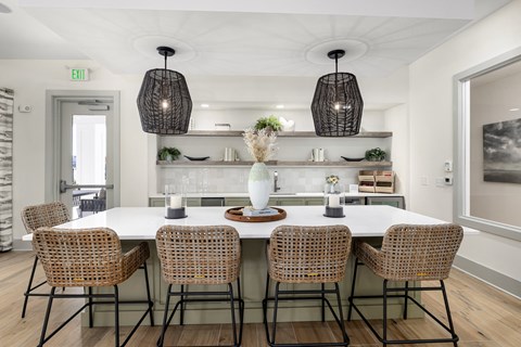 a dining room with a large white table and rattan chairs