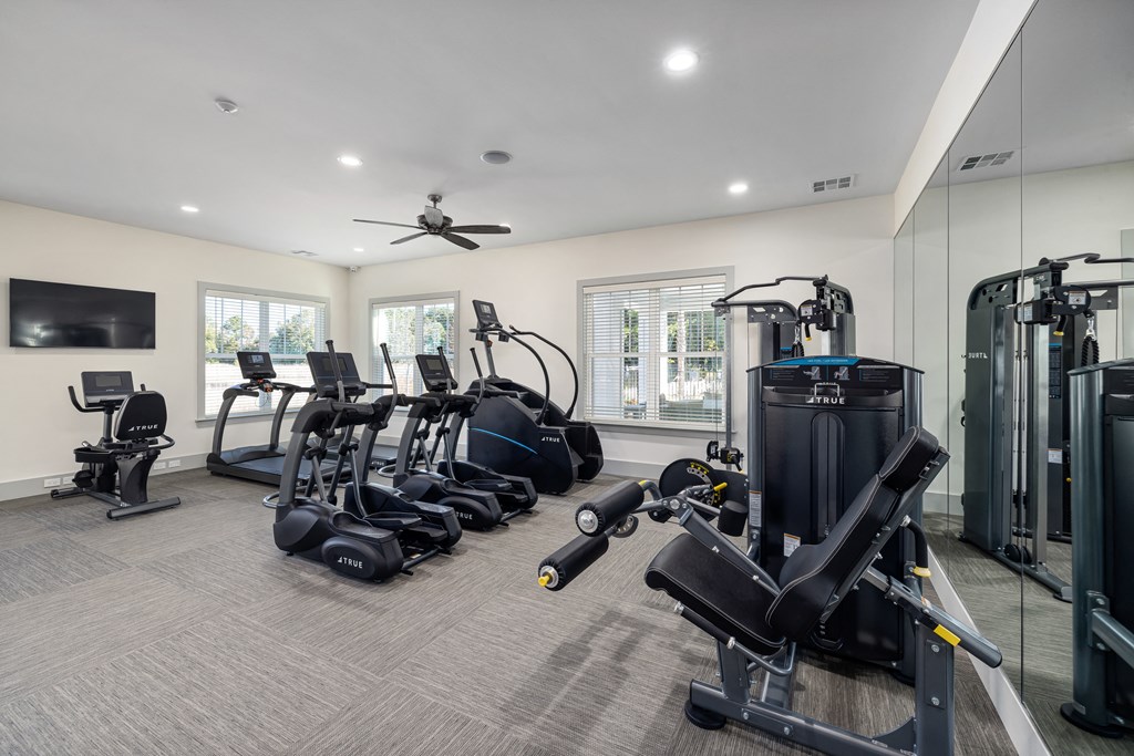 a gym with cardio machines and a tv
