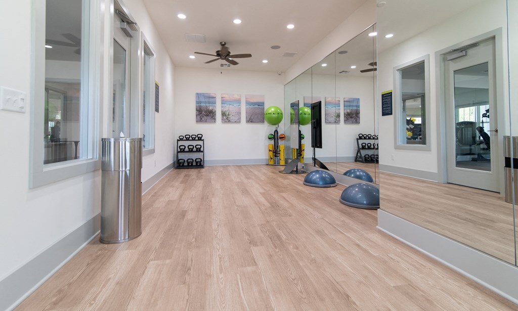 a yoga room with mirrors and a ceiling fan and a wood floor
