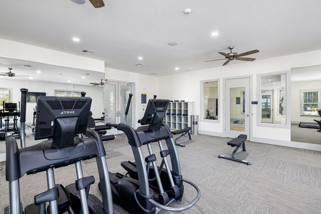 a gym with treadmills and other exercise equipment in a building with white walls