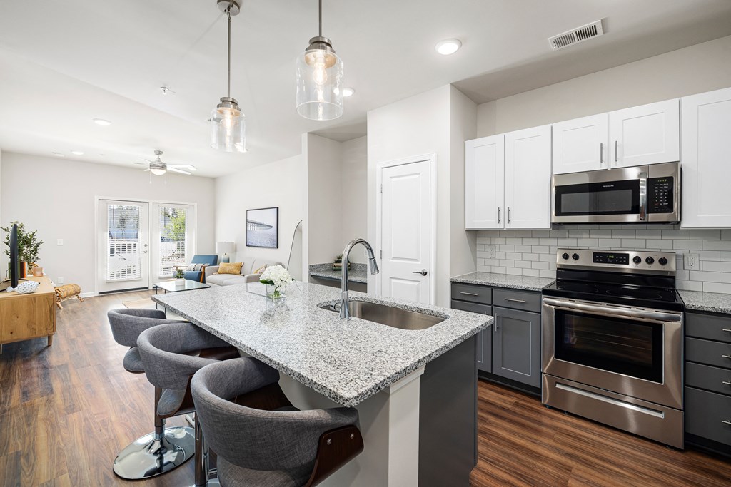 an open kitchen and living room with a marble counter top