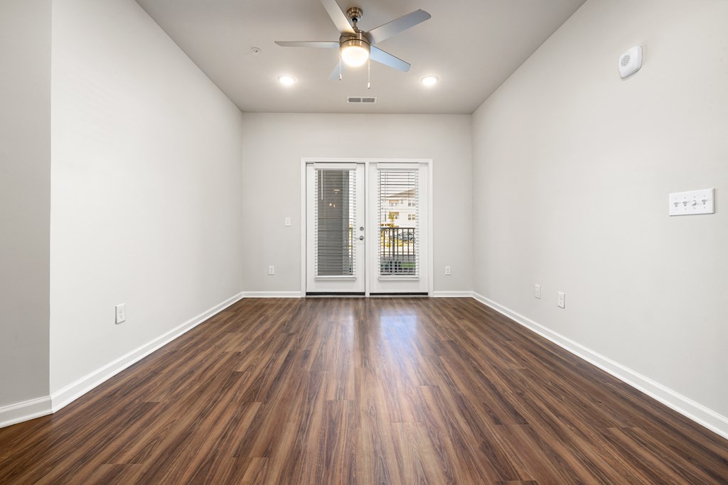 an empty living room with wood flooring and a ceiling fan