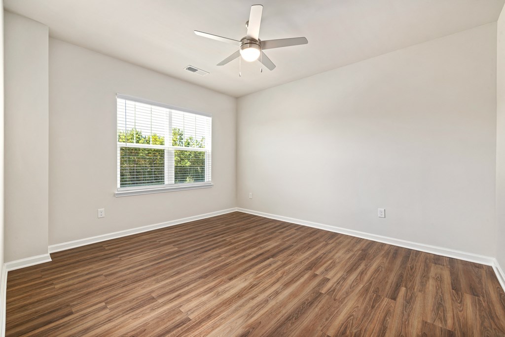 an empty living room with wood floors and a ceiling fan