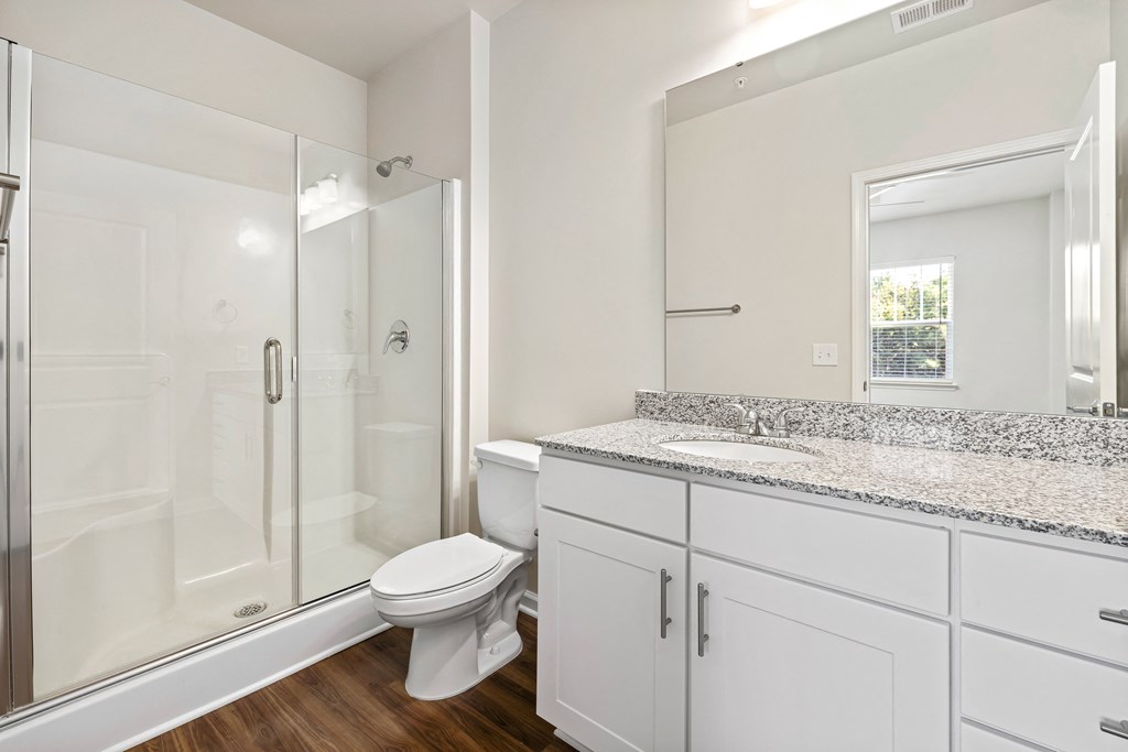 a bathroom with white cabinets and a toilet and a shower