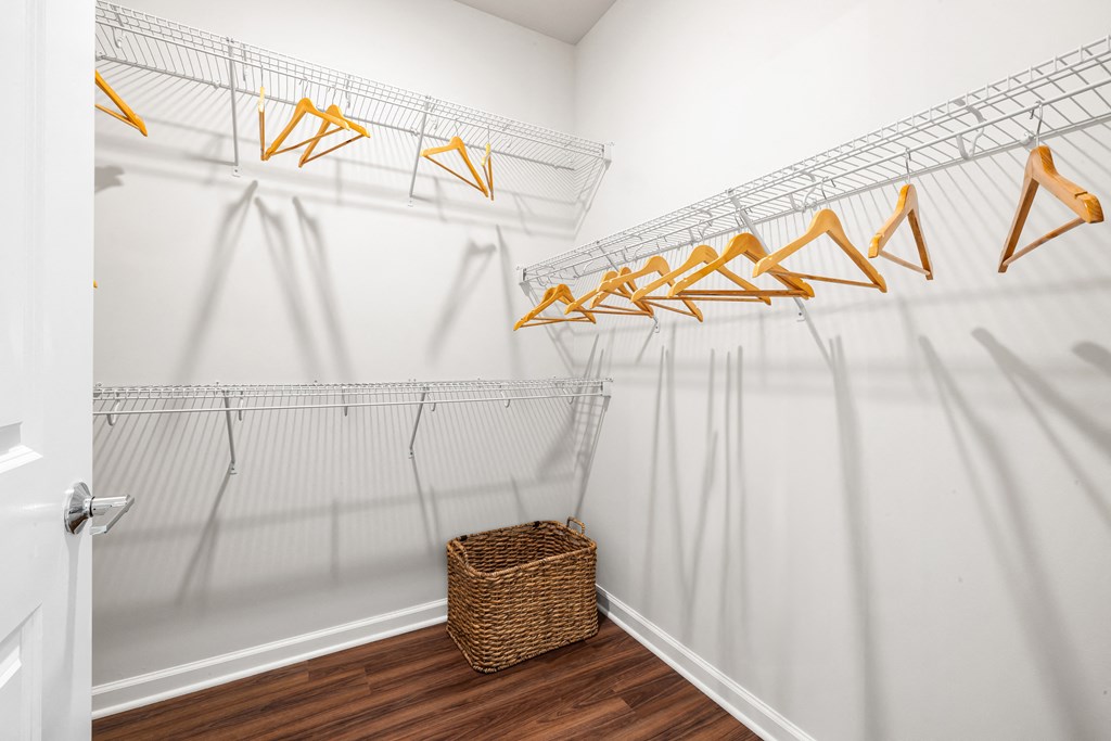 a walk in closet with white walls and a basket on the floor