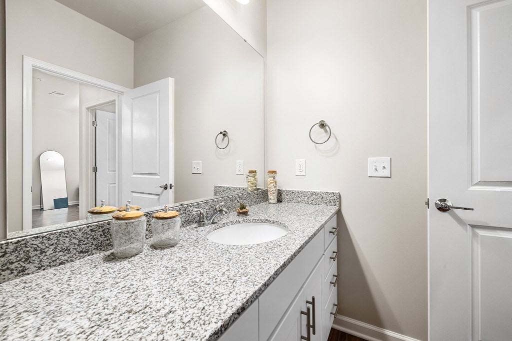 a bathroom with granite counter top and a mirror