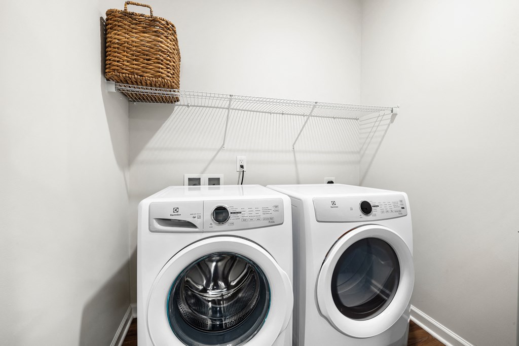 a white washer and dryer in a laundry room with a shelf above them